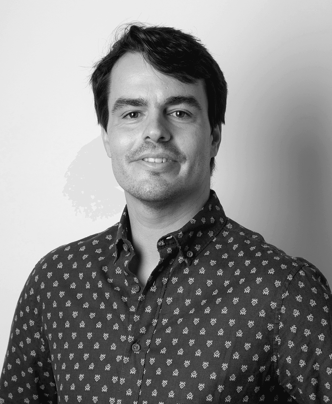 Retrato em preto e branco de Joao Garcia, olhando diretamente para a câmera com um leve sorriso