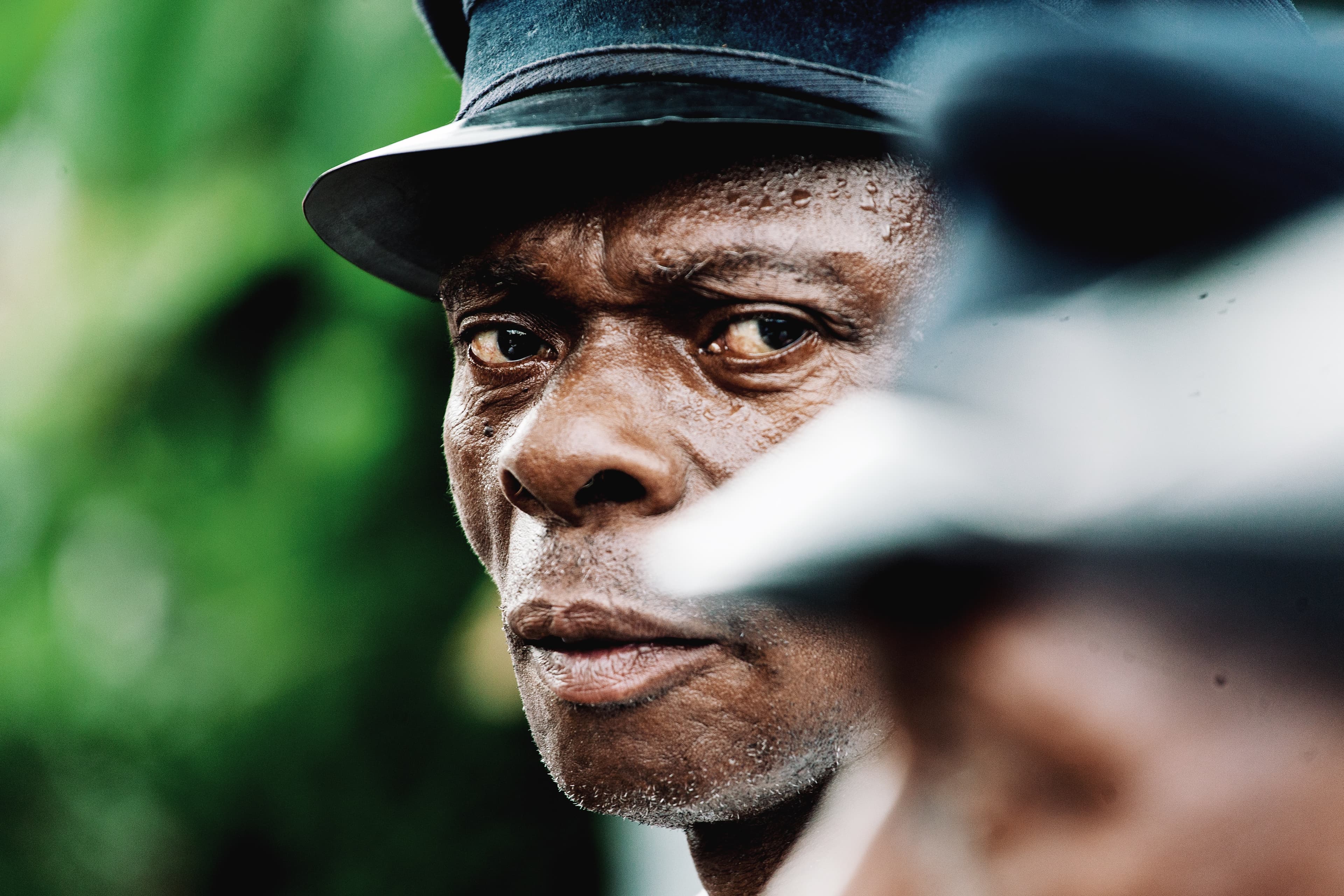 A man looks expressively into the camera, wearing a black hat on his head